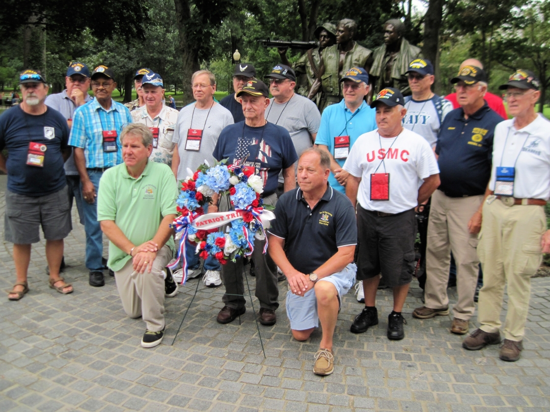 Assemblyman Steve Hawley [right of wreath] poses for a photo with Assemblyman Michael DenDekker [left of wreath] and veterans in front of the Vietnam War Memorial during 2018’s Patriot Trip to Wa
